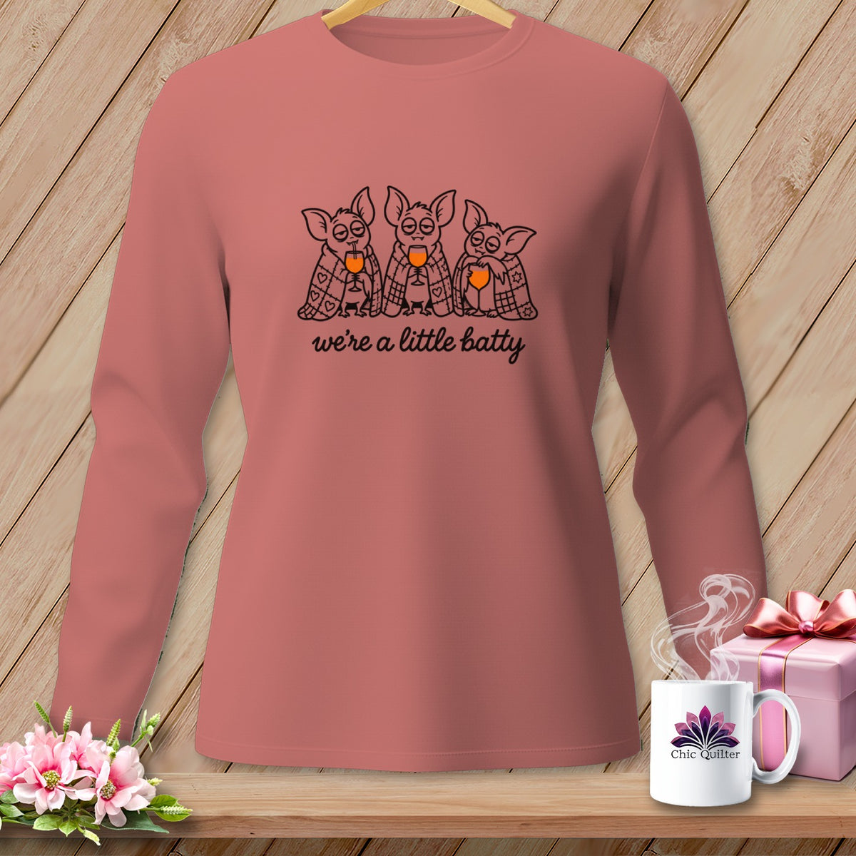 Pink long-sleeve shirt with three cartoon bats drinking wine and text "we're a little batty".