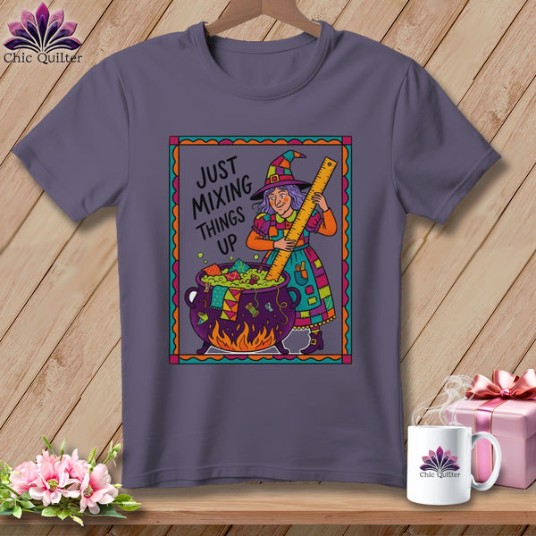 Purple t-shirt with a witch stirring a cauldron, reads "Just Mixing Things Up".