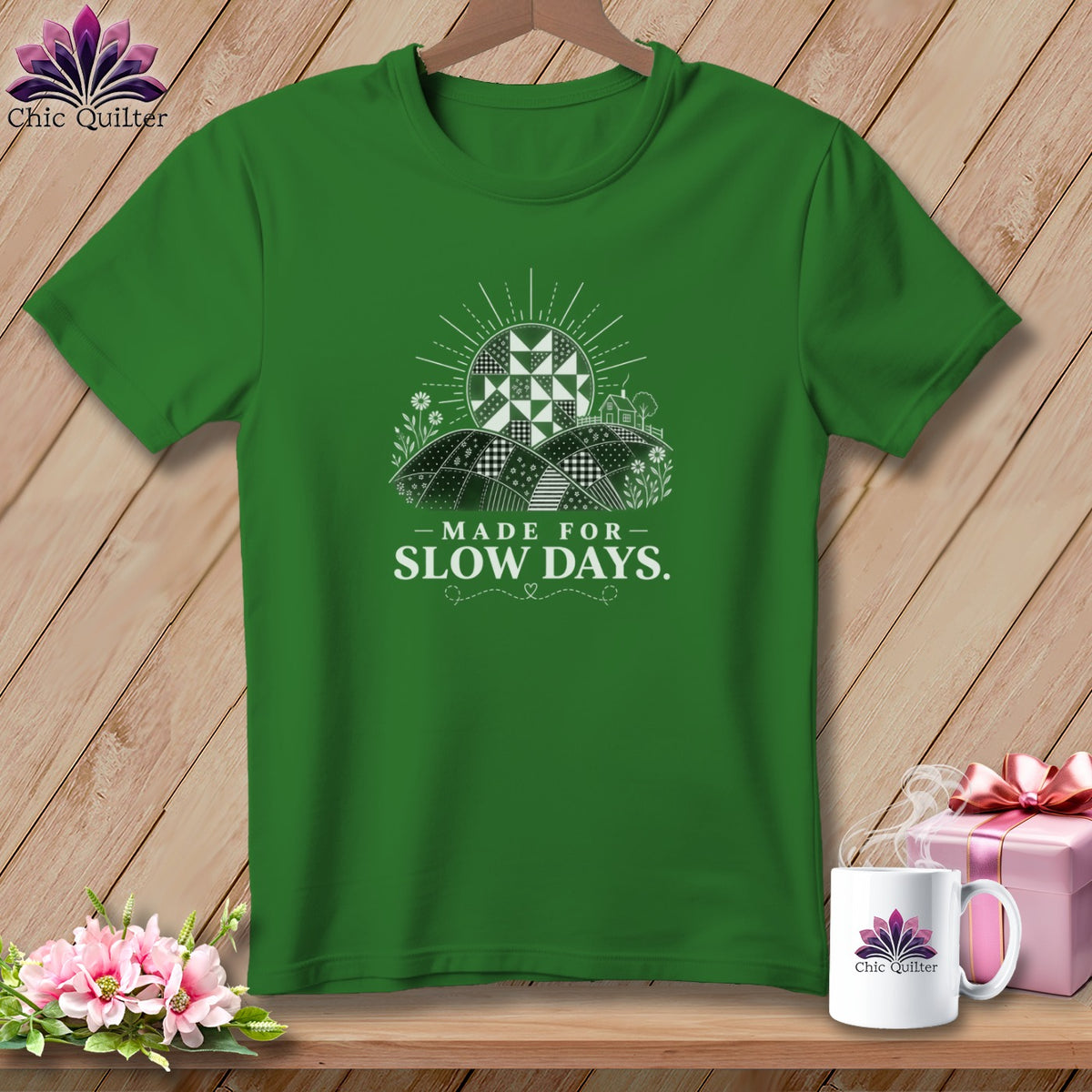 Green t-shirt with white graphic featuring a sun and quilted landscape, text "MADE FOR SLOW DAYS."