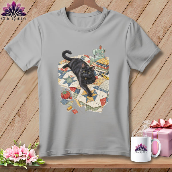 Black cat lying on a quilt with sewing supplies and a miniature sewing machine.