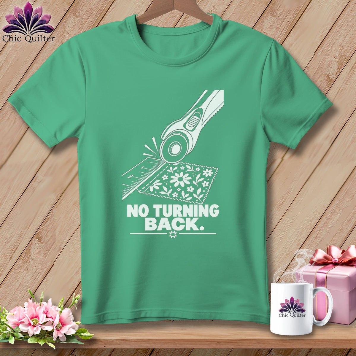 Green t-shirt with white graphic of rotary cutter, ruler, fabric, and text "NO TURNING BACK".