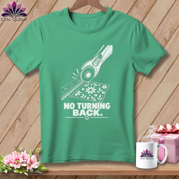Green t-shirt with white graphic of rotary cutter, ruler, fabric, and text "NO TURNING BACK".