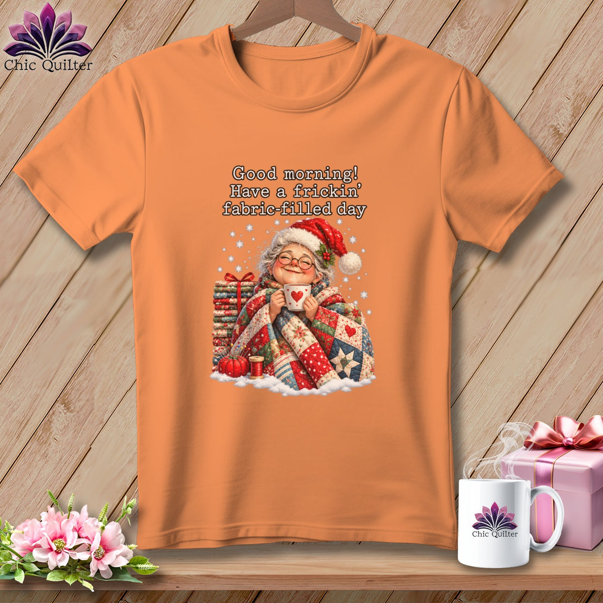 An orange t-shirt displays an illustrated graphic of an elderly woman holding a mug with text above her reading Good morning! Have a frickin fabric filled day.