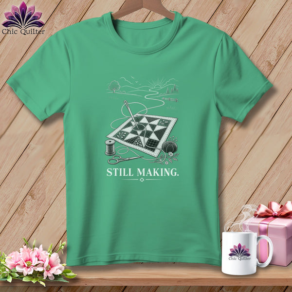 Green t-shirt featuring a quilt, sewing supplies, and text "STILL MAKING."
