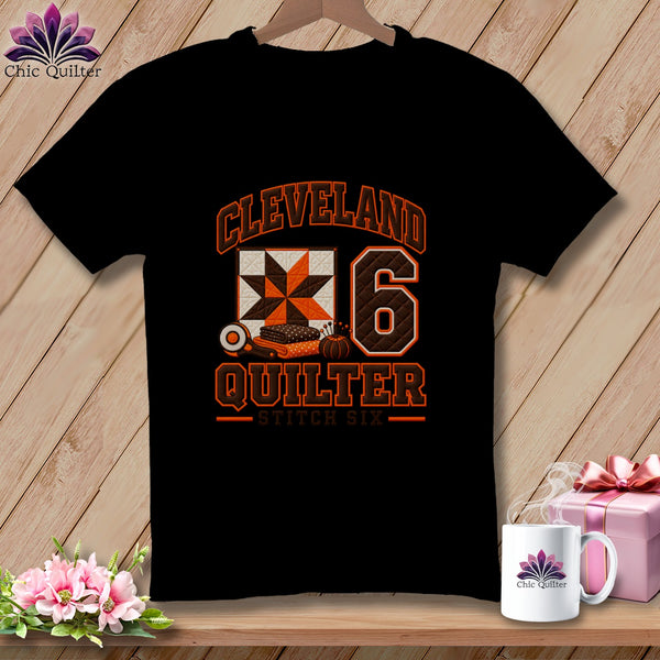 Black t-shirt featuring a Cleveland Quilter graphic with a quilt block, rotary cutter, and the number six.