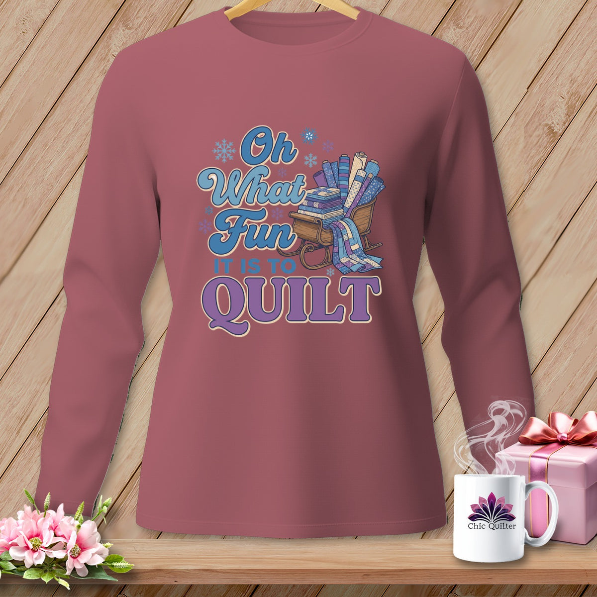 Long sleeve shirt with "Oh What Fun It Is To Quilt" text and a sleigh of fabric rolls.