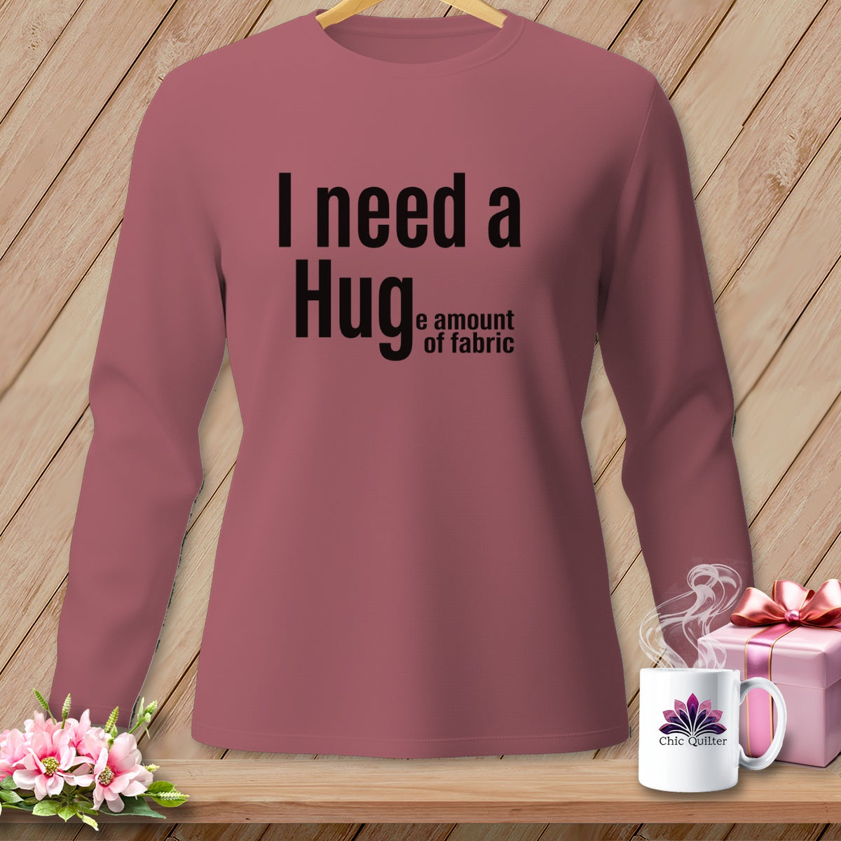 Rose long-sleeve shirt with black text: "I need a Hug e amount of fabric."