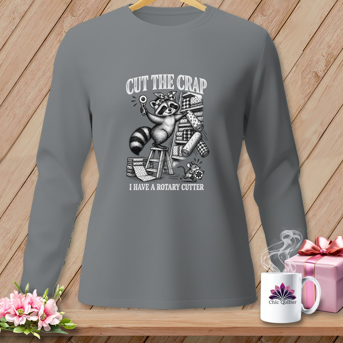 Long-sleeved grey shirt with a graphic of a raccoon holding a rotary cutter and text.