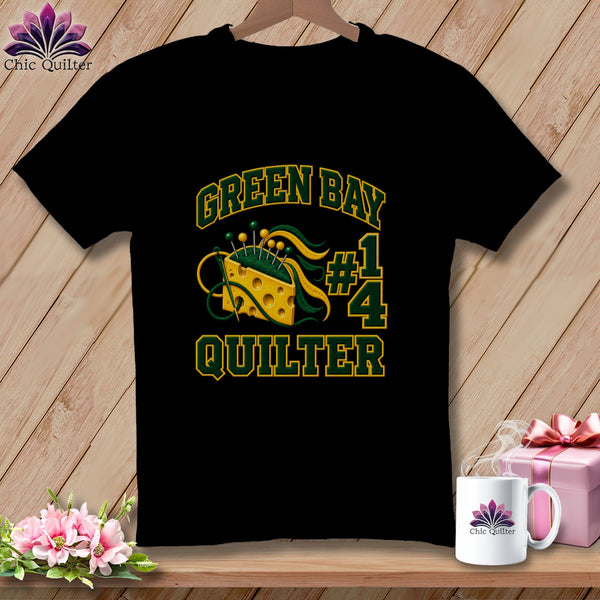 A black t-shirt features Green Bay Quilter text alongside a Swiss cheese pin cushion graphic.
