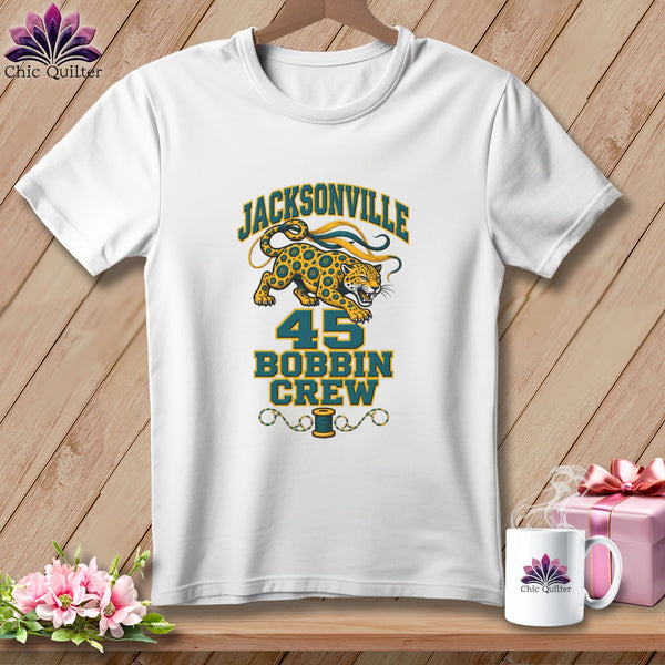 A white t-shirt features a graphic with a jaguar, the text Jacksonville 45 Bobbin Crew, and a thread spool.
