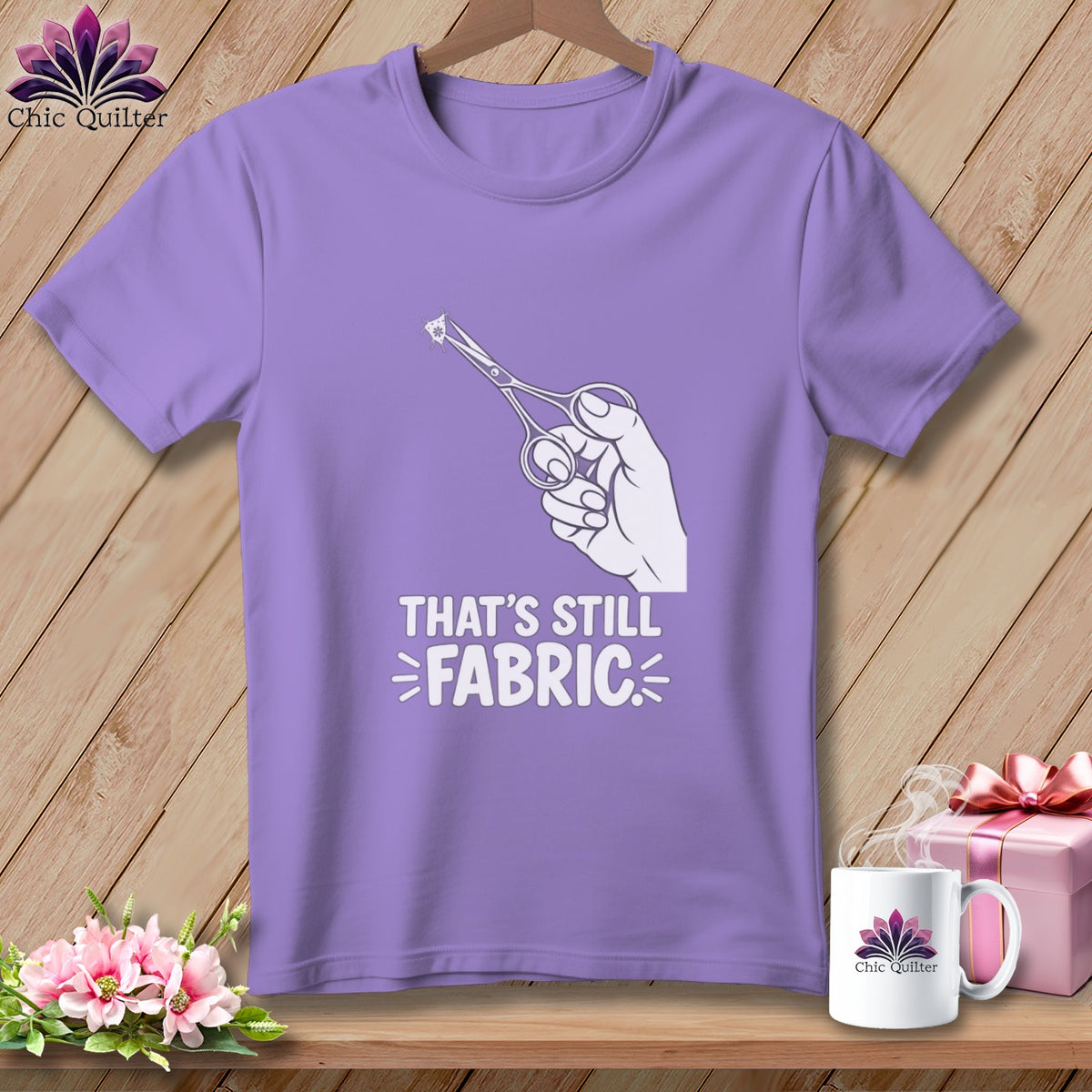 Purple t-shirt with a hand holding scissors cutting a small piece of fabric and the text "That's still fabric".