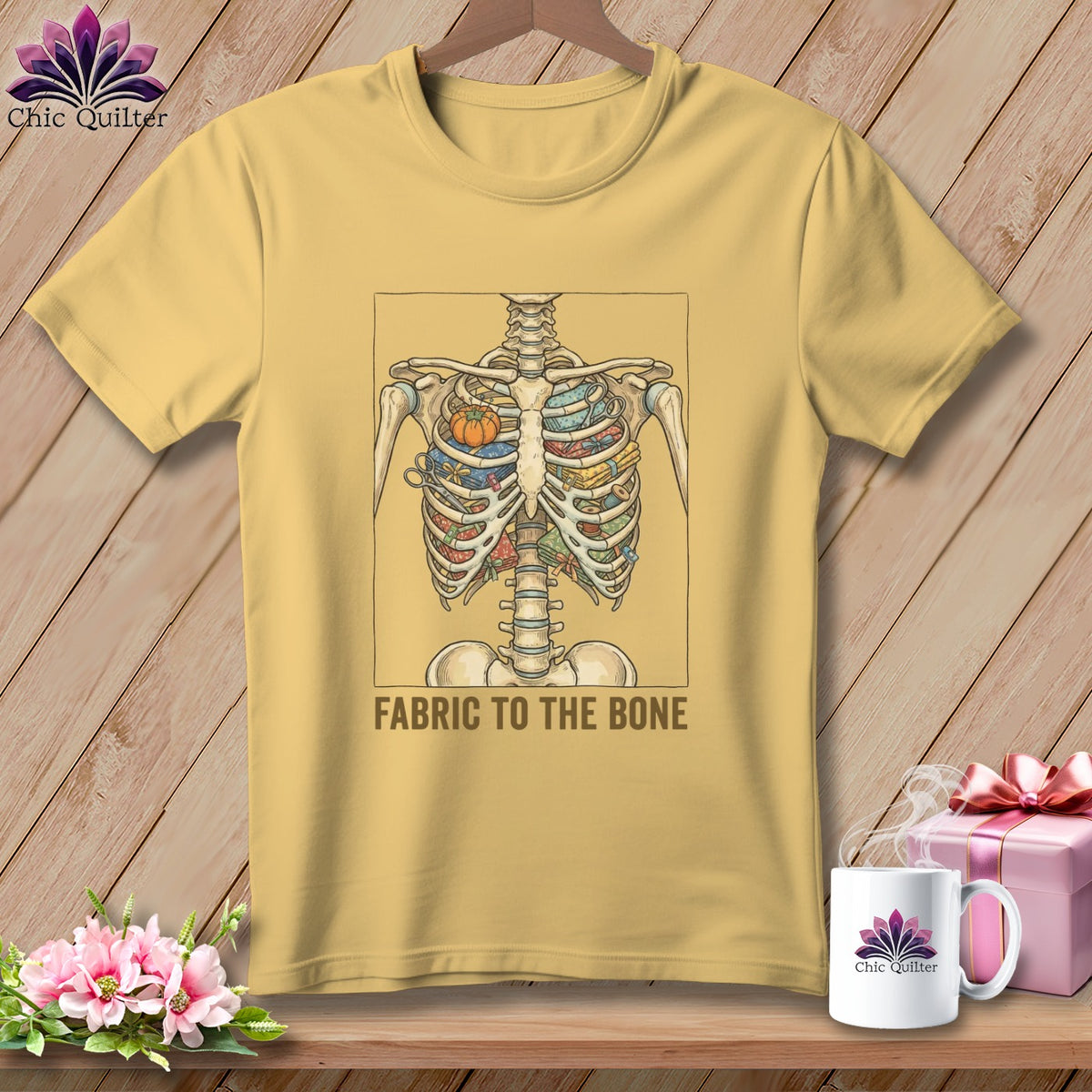Yellow t-shirt with a skeleton ribcage filled with fabric and a pumpkin pin cushion. Text reads: FABRIC TO THE BONE.