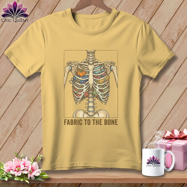 Yellow t-shirt with a skeleton ribcage filled with fabric and a pumpkin pin cushion. Text reads: FABRIC TO THE BONE.