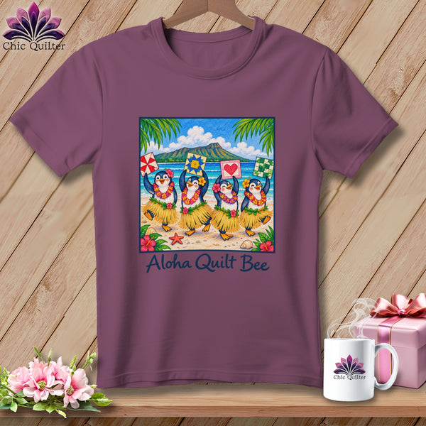 Plum t-shirt featuring a graphic of four hula-dancing penguins on a beach with the text Aloha Quilt Bee.