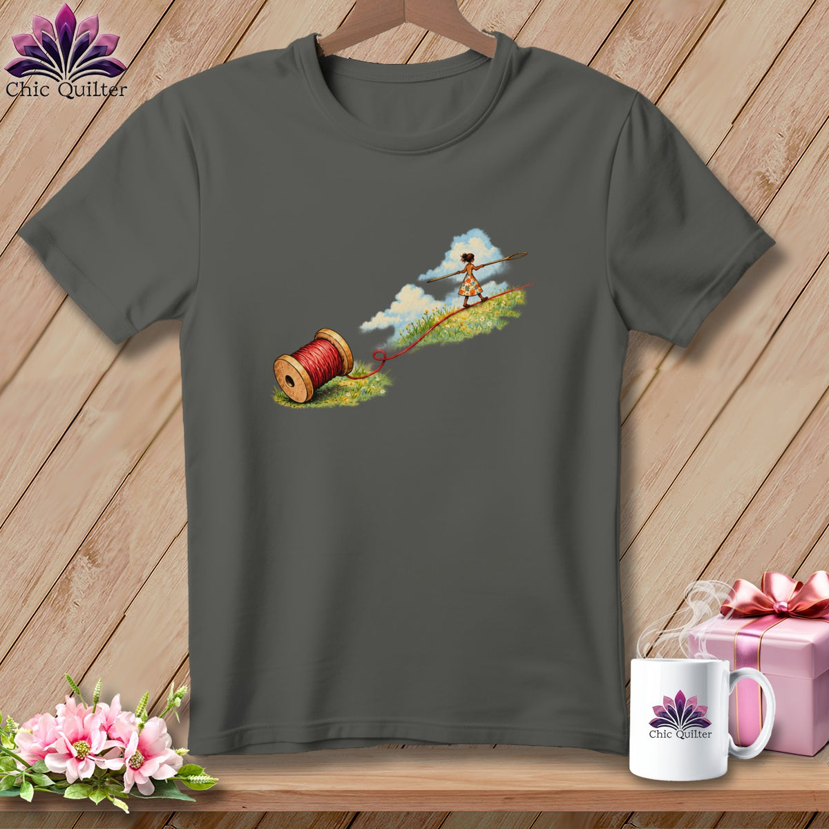 A dark gray t-shirt featuring a graphic of a girl tightrope walking on red thread.