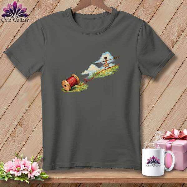 A dark gray t-shirt featuring a graphic of a girl tightrope walking on red thread.
