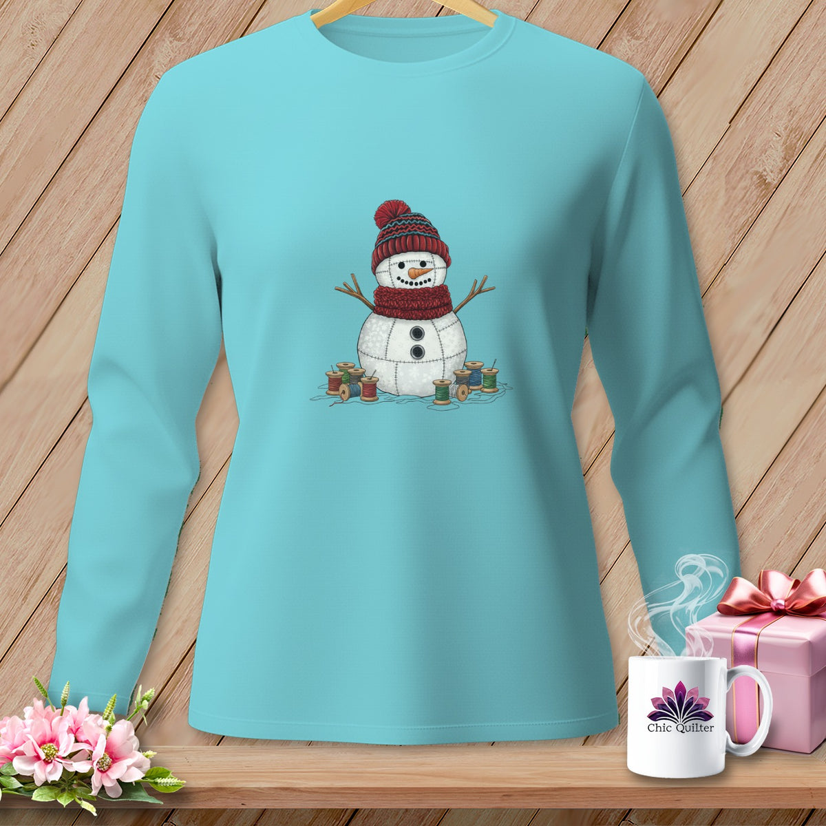 Aqua long-sleeve shirt with a quilted snowman graphic and spools of thread.