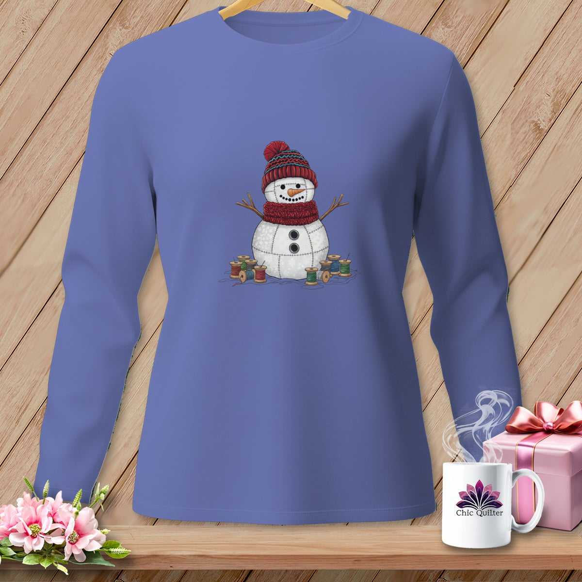 Lavender long-sleeve shirt with a patched snowman design and spools of thread.