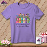 A purple t-shirt features a graphic of rolled fabric, flowers, and the text 