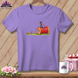 Light purple crewneck t-shirt featuring an illustration of a woman riding a giant spool of red thread.