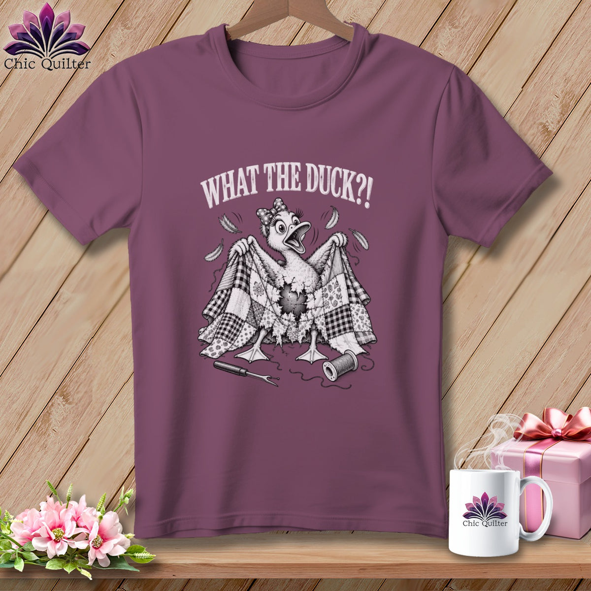 Plum crewneck t-shirt featuring a cartoon duck holding a torn quilt, with text reading WHAT THE DUCK?!