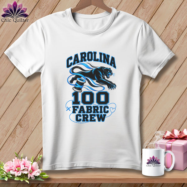 A white t-shirt hanging on a wooden background features a blue panther graphic with the text CAROLINA 100 FABRIC CREW.