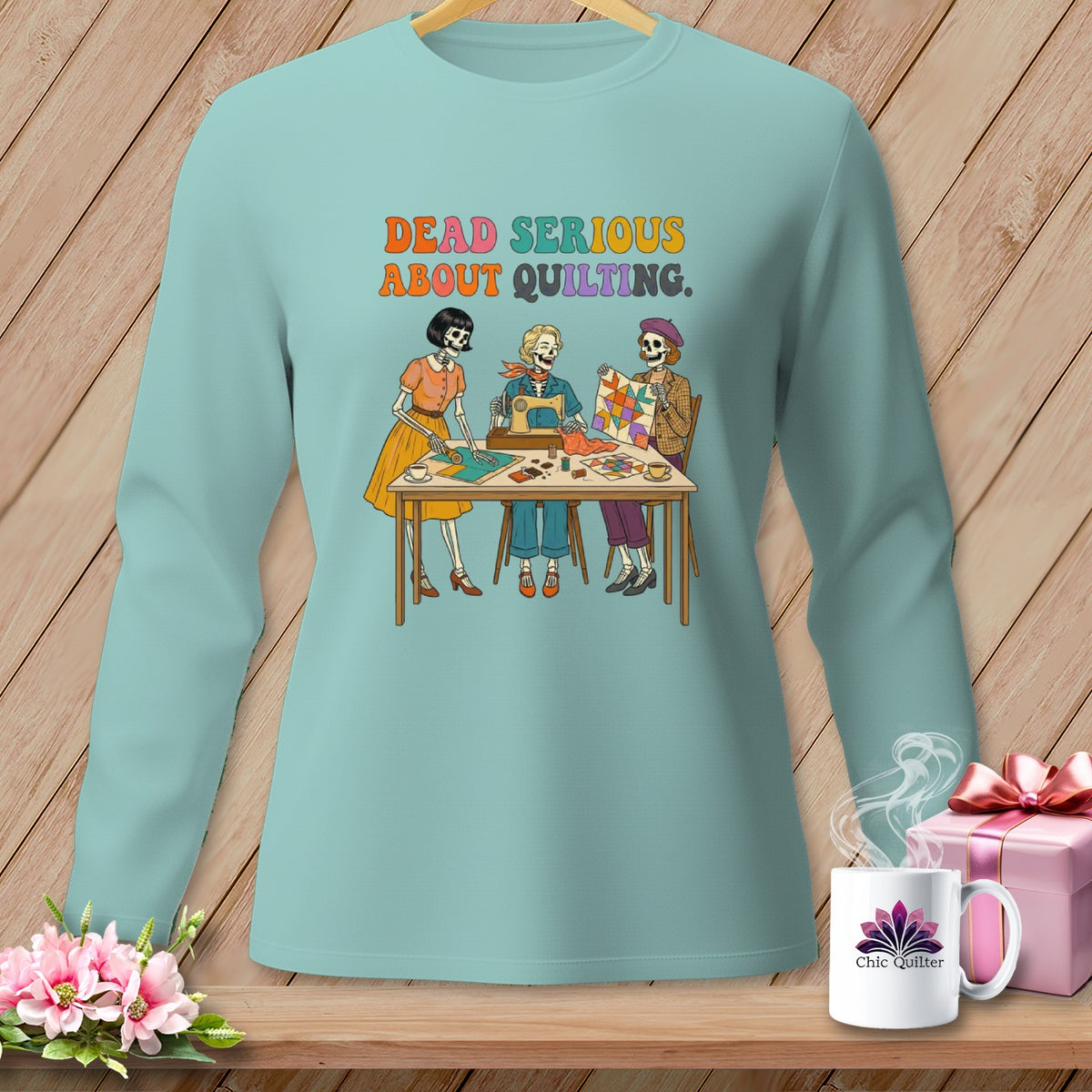 Skeletons quilting with text "DEAD SERIOUS ABOUT QUILTING" on a light blue shirt.