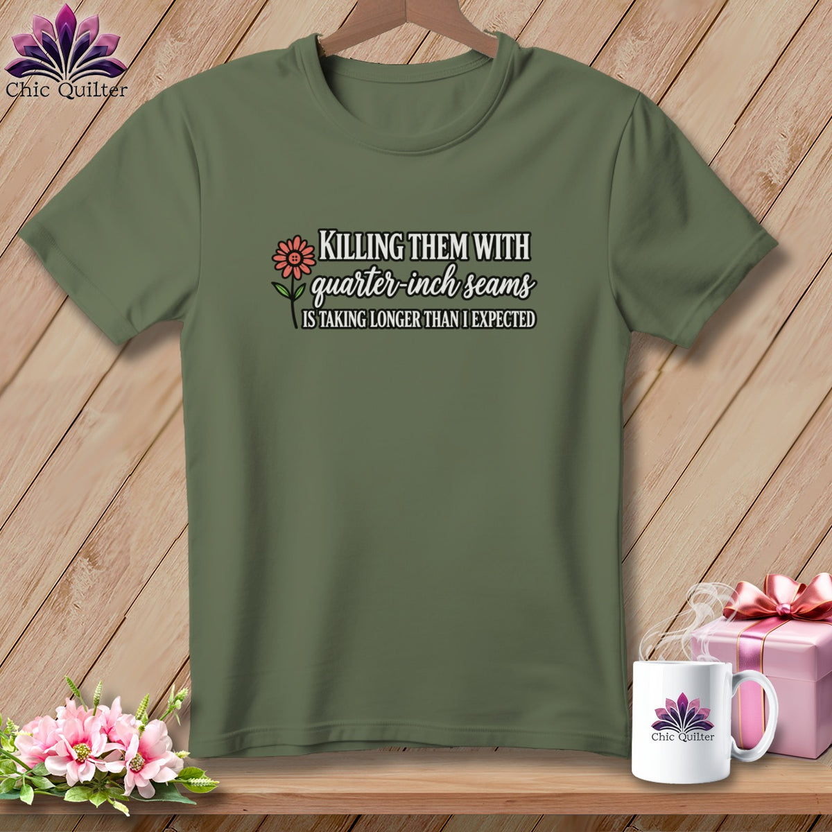 An olive green t-shirt with white and pink text reading, Killing them with quarter inch seams is taking longer than I expected.