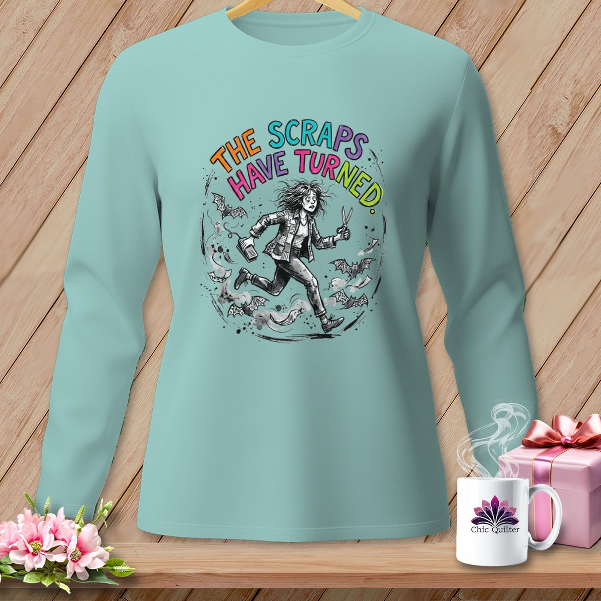Light blue long-sleeve shirt with graphic of running woman and text "The Scraps Have Turned."