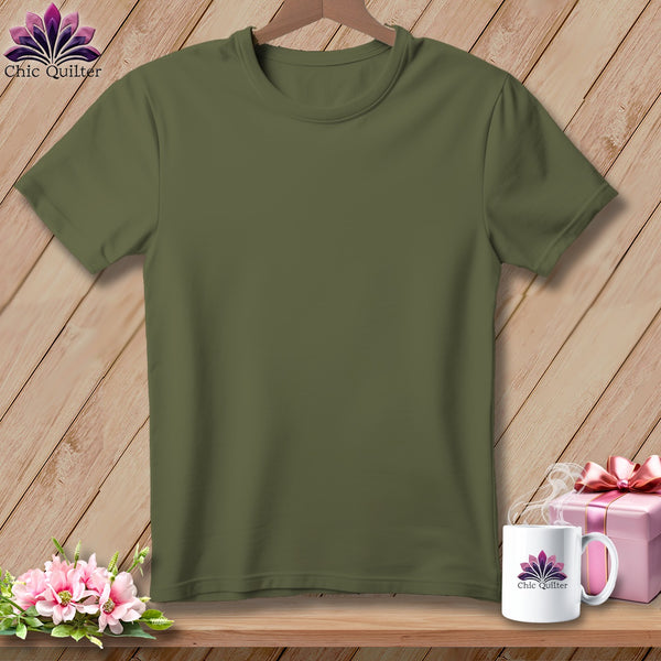 Olive green t-shirt on a wooden background with flowers and a mug.