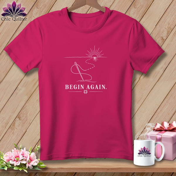 Pink t-shirt with "BEGIN AGAIN." and sewing needle design.