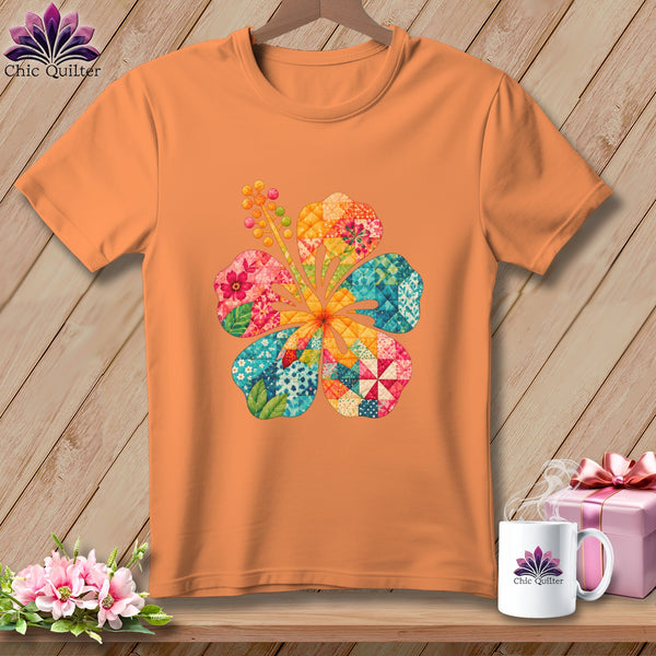 Orange short-sleeved t-shirt hanging on a wooden wall, featuring a colorful patchwork hibiscus flower graphic.