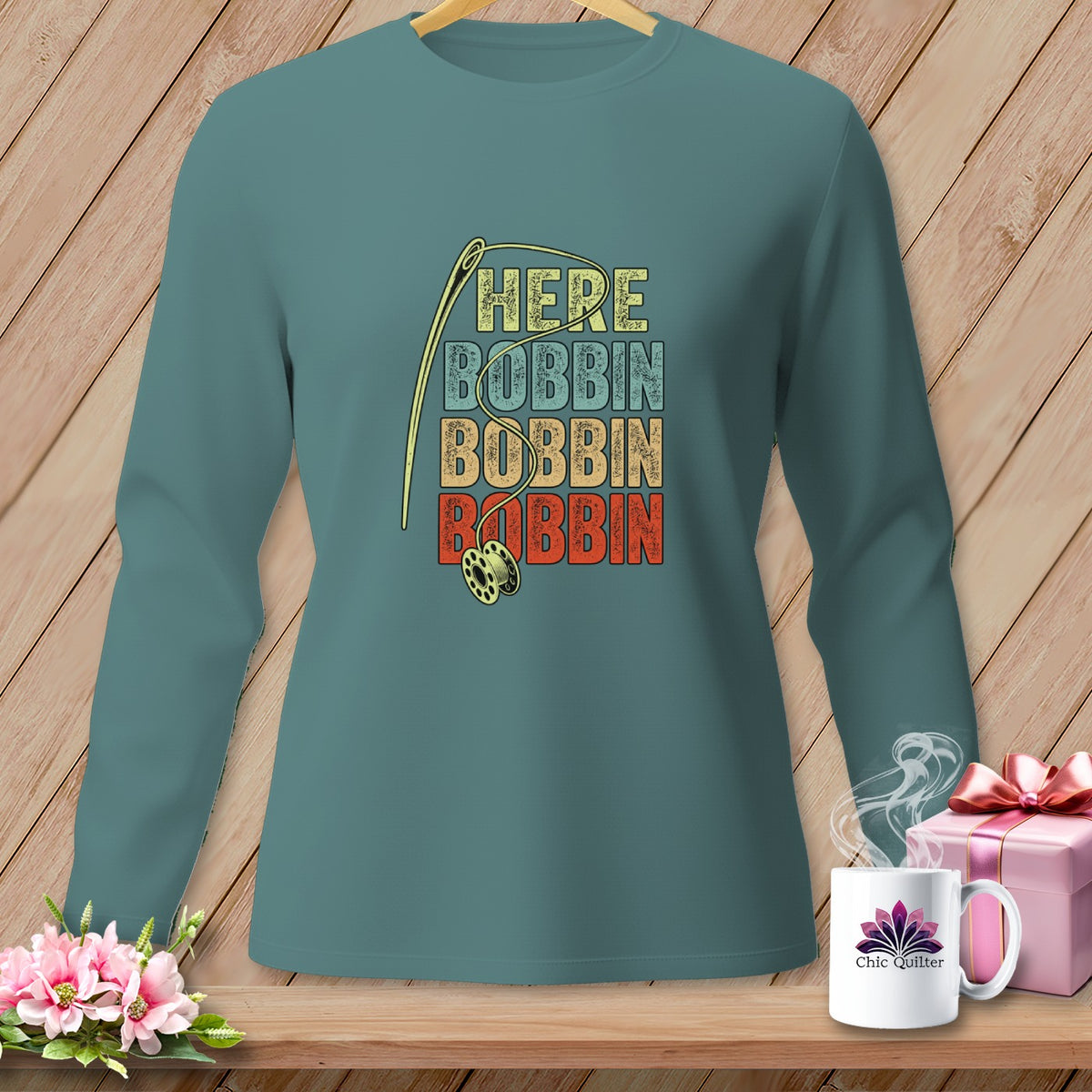 Teal long-sleeve shirt with "HERE BOBBIN BOBBIN BOBBIN" text and sewing needle.