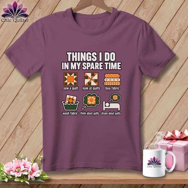 A plum-colored t-shirt on a wooden hanger with graphic text detailing quilting activities.
