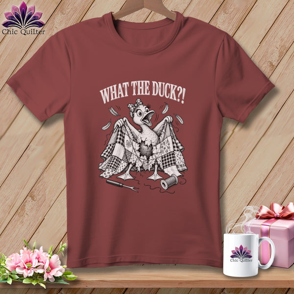 Maroon t-shirt featuring a cartoon duck holding up a tattered quilt with the text WHAT THE DUCK?!