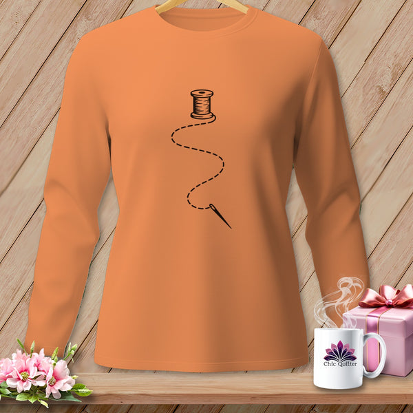 Orange long-sleeve shirt with black spool of thread, needle, and dashed line design.