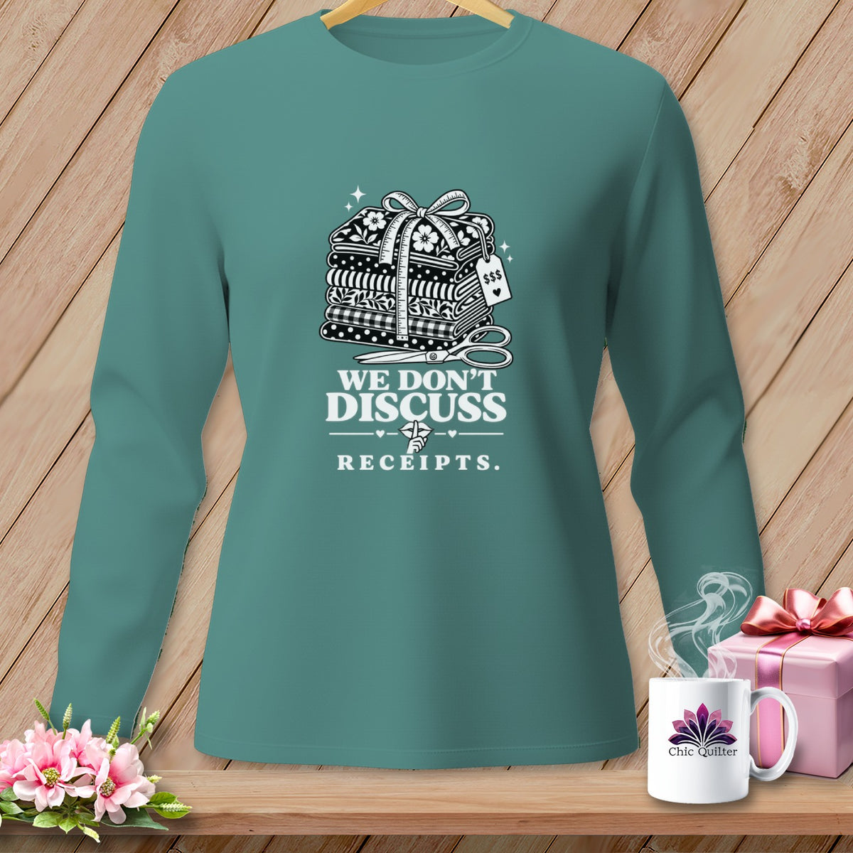 Teal long-sleeve shirt with stack of fabric, scissors, and "We Don't Discuss Receipts" text.