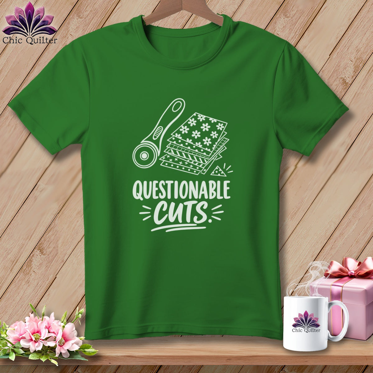 Green t-shirt with white graphic of rotary cutter, fabric stacks, and text "QUESTIONABLE CUTS".