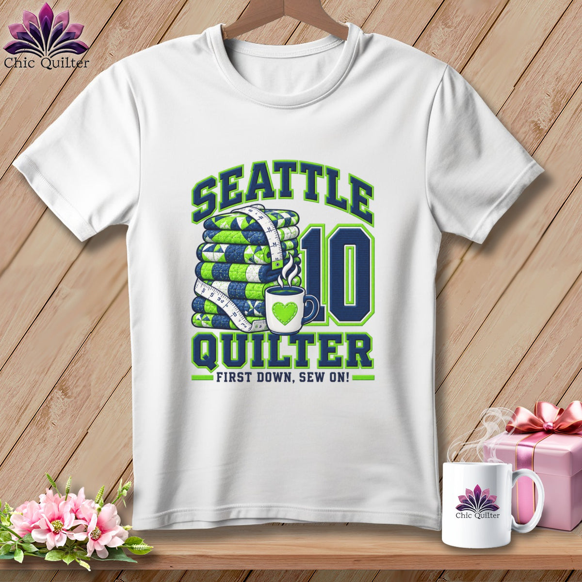 A white t-shirt features a Seattle Quilter 10 design with a stack of quilts and a mug.