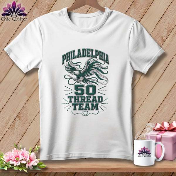 White t-shirt with a green graphic featuring an eagle, the text PHILADELPHIA 50 THREAD TEAM, and a needle.