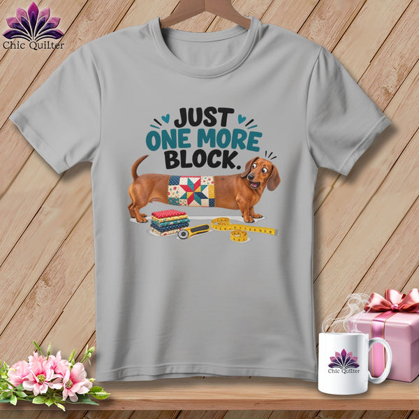 Dachshund wearing a quilt block with "Just One More Block" text.