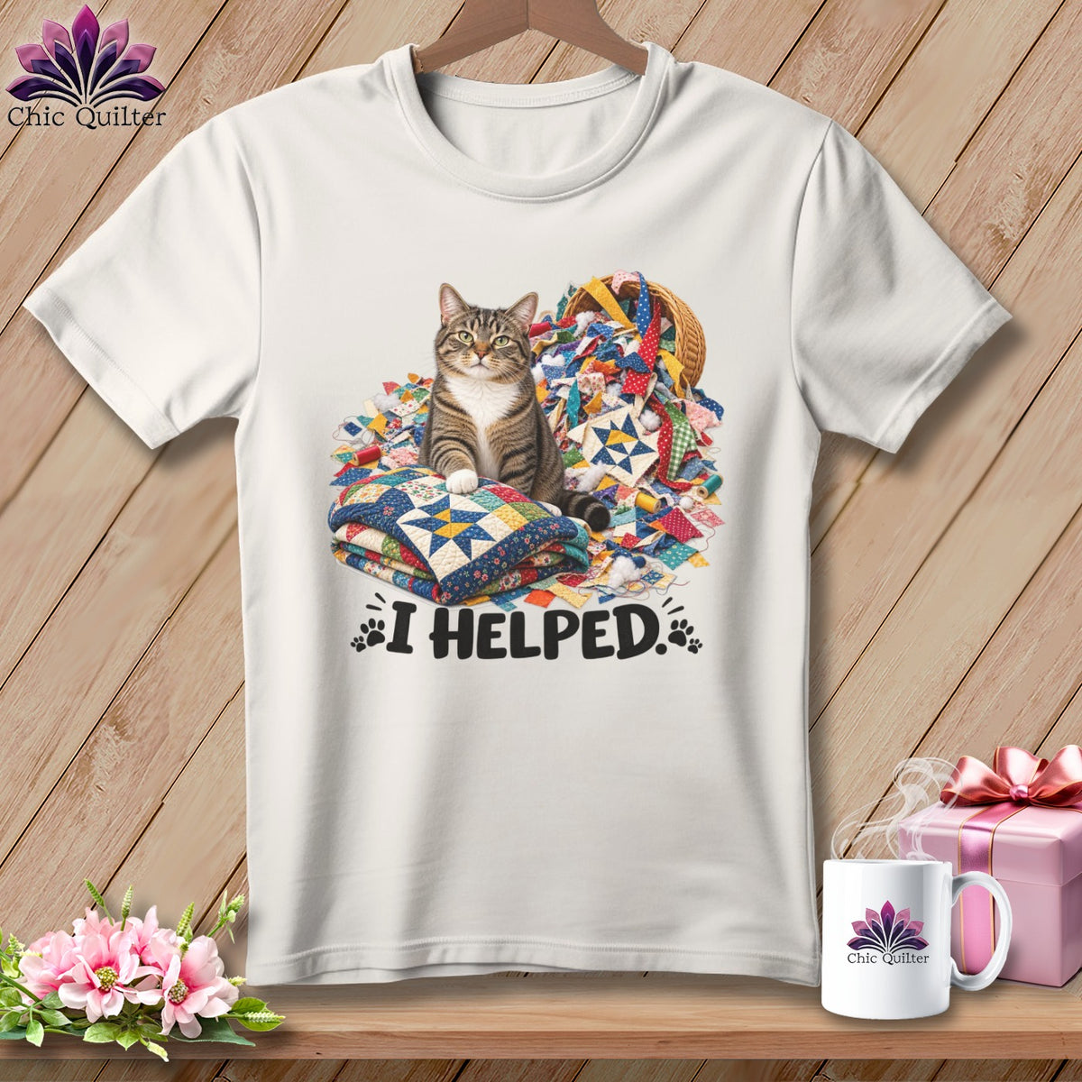 Tabby cat sits on quilt stacks near basket of quilting scraps, with "I HELPED." text.