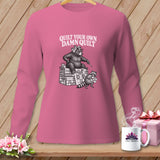 Pink long-sleeved shirt with a graphic of a bear and raccoon quilting and the text Quilt Your Own Damn Quilt.