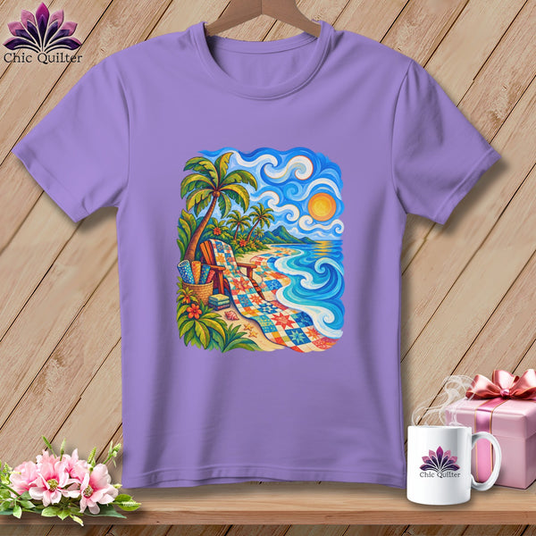 A light purple t-shirt featuring a vibrant graphic of a tropical beach scene with a colorful quilt draped on the sand.