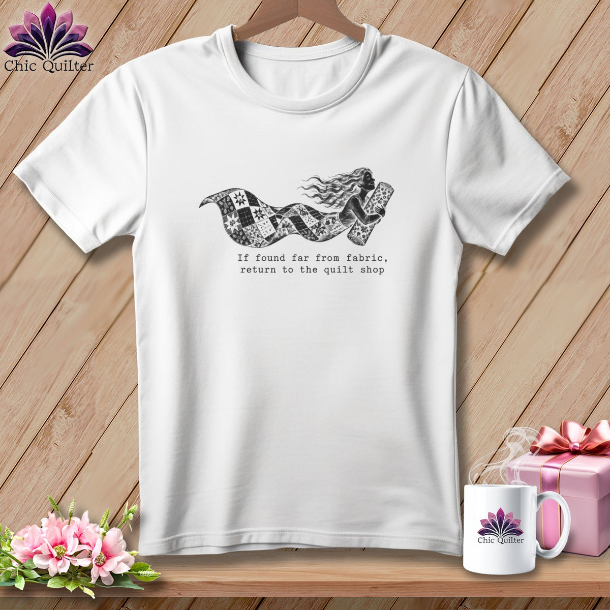 White t-shirt with a graphic of a woman flowing in a quilt, and text.