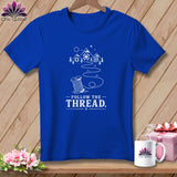 Blue t-shirt with white graphic of a spool of thread, mountains, and trees, reading 