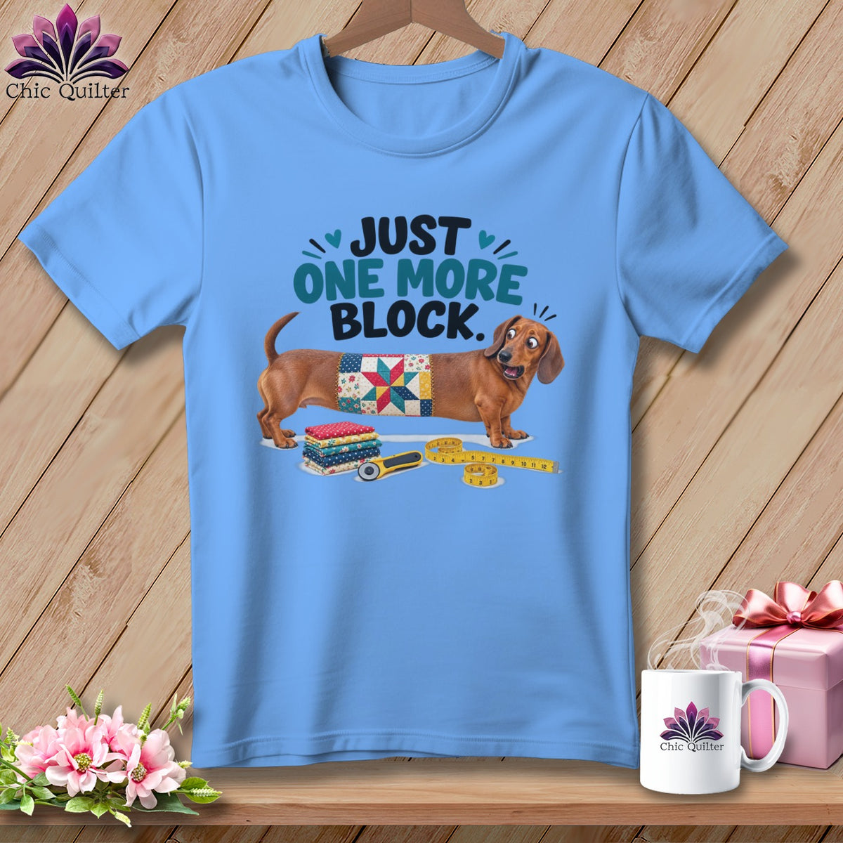 Light blue t-shirt with dachshund and quilting motif saying "Just One More Block."