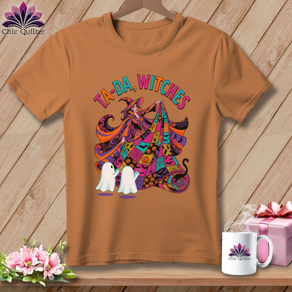 Brown t-shirt with a Halloween graphic of a witch and ghosts, text reads "Ta-Da, Witches".