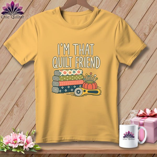 Yellow crewneck t-shirt featuring the text I AM THAT QUILT FRIEND above stacked patterned fabrics and sewing tools.