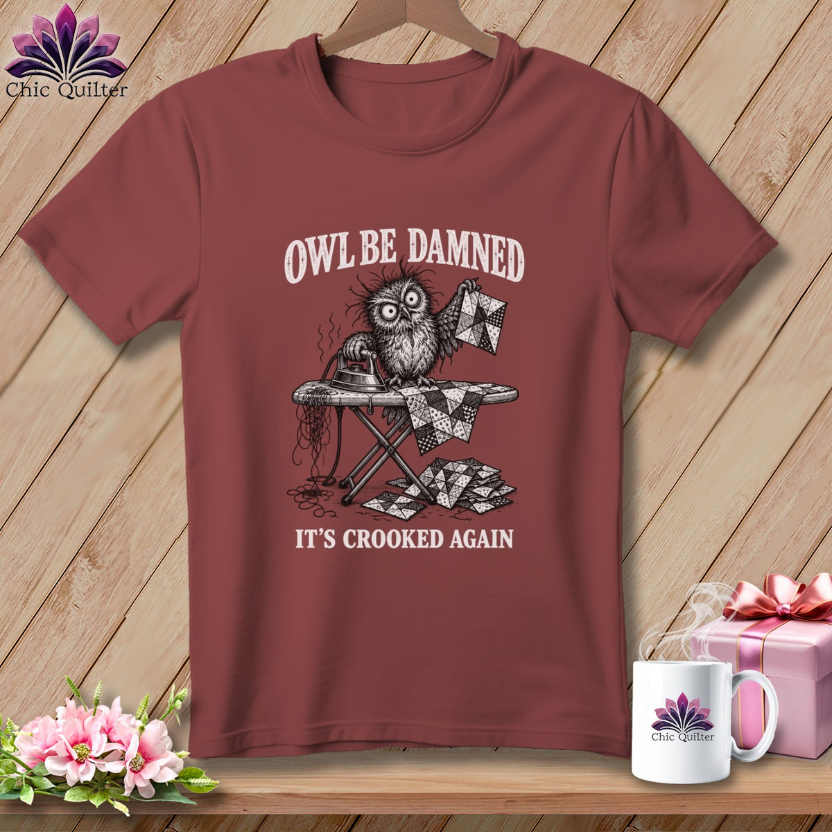 Maroon t-shirt with an owl ironing a quilt, text "OWL BE DAMNED" and "IT'S CROOKED AGAIN".